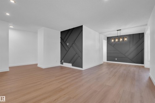 Unfurnished room featuring a barn door, light wood-style floors, and a textured ceiling - 1111 49A Street, Edmonton, AB - Indoor Photo Showing Other Room