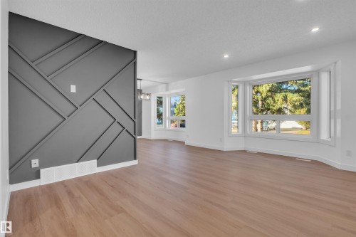 Unfurnished living room featuring a chandelier, light wood finished floors, recessed lighting, and a textured ceiling - 1111 49A Street, Edmonton, AB - Indoor