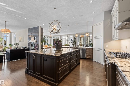 Kitchen with pendant lighting, open floor plan, light stone counters, dark wood-style floors, and a chandelier - 2796 Wheaton Drive, Edmonton, AB - Indoor Photo Showing Kitchen With Upgraded Kitchen