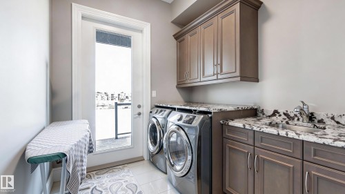 Laundry area with cabinet space, independent washer and dryer, and light tile patterned floors - 2796 Wheaton Drive, Edmonton, AB - Indoor Photo Showing Laundry Room