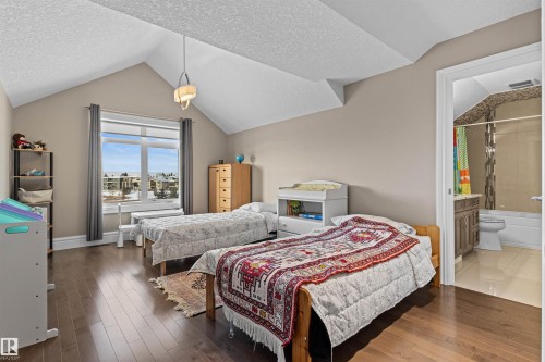 Bedroom with a textured ceiling, vaulted ceiling, wood finished floors, and connected bathroom - 2796 Wheaton Drive, Edmonton, AB - Indoor Photo Showing Bedroom