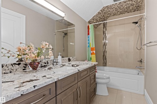 Bathroom with vanity, shower / tub combo with curtain, a textured ceiling, and light tile patterned floors - 2796 Wheaton Drive, Edmonton, AB - Indoor Photo Showing Bathroom