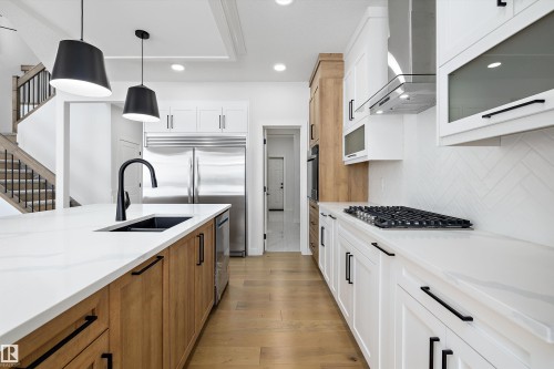 Kitchen with two tone cabinets, light wood-style flooring, pendant lighting, light stone counters, and stainless steel appliances - 230 Edgemont Green Green Nw, Edmonton, AB - Indoor Photo Showing Kitchen With Double Sink With Upgraded Kitchen
