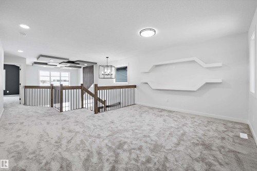 Carpeted spare room featuring baseboards and hanging lights - 230 Edgemont Green Green Nw, Edmonton, AB - Indoor Photo Showing Other Room