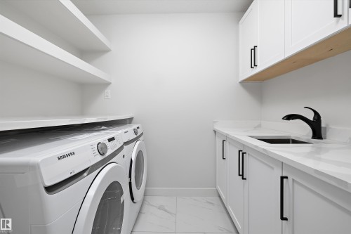 Laundry area featuring light marble finish floors, washing machine and dryer, and cabinet space - 230 Edgemont Green Green Nw, Edmonton, AB - Indoor Photo Showing Laundry Room