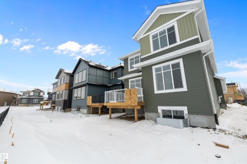 Snow covered house with board and batten siding, a wooden deck, and a residential view - 230 Edgemont Green Green Nw, Edmonton, AB - Outdoor