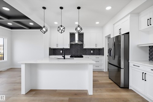 Kitchen with stainless steel fridge, white cabinetry, light wood finished floors, light stone countertops, and recessed lighting - 38 Cannes Cove, St. Albert, AB - Indoor Photo Showing Kitchen With Upgraded Kitchen