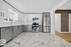 Kitchen with gray cabinetry, stainless steel appliances, light marble finish flooring, and white cabinetry - 