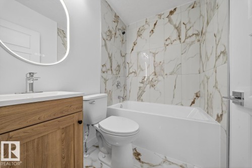 Full bath featuring bathtub / shower combination, vanity, and marble finish flooring - 12919 113A Street, Edmonton, AB - Indoor Photo Showing Bathroom