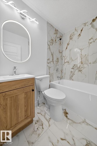 Full bath featuring vanity, bathtub / shower combination, light marble finish flooring, and a textured ceiling - 12919 113A Street, Edmonton, AB - Indoor Photo Showing Bathroom