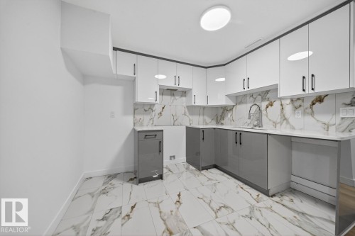 Kitchen with white cabinetry, modern cabinets, light stone counters, gray cabinetry, and light marble finish floors - 12919 113A Street, Edmonton, AB - Indoor Photo Showing Kitchen