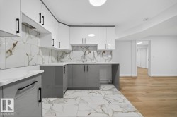 Kitchen featuring white cabinetry, gray cabinetry, light stone counters, light marble finish flooring, and decorative backsplash - 