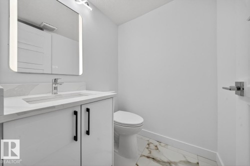 Bathroom featuring vanity, marble look tile flooring, and a textured ceiling - 12919 113A Street, Edmonton, AB - Indoor Photo Showing Bathroom