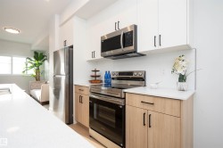 Kitchen with stainless steel appliances, decorative backsplash, light stone countertops, white cabinets, and modern cabinets - 