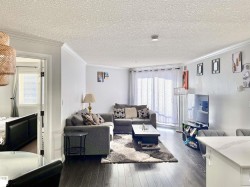 Living room with a textured ceiling, dark wood-style flooring, and ornamental molding - 