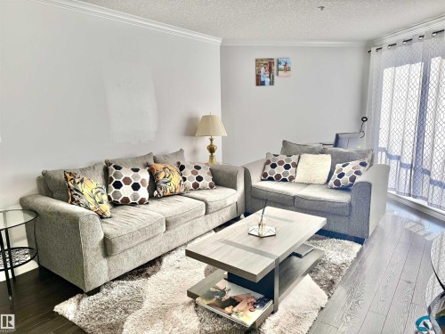 Living room featuring dark wood-style flooring, a textured ceiling, and ornamental molding - 205 14604 125 Street, Edmonton, AB - Indoor Photo Showing Living Room