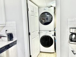 Washroom featuring stacked washing machine and dryer, a paneled ceiling, and dark speckled floor - 