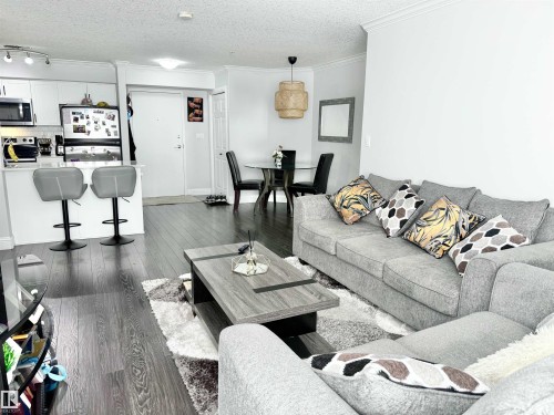 Living area with dark wood-style floors, a textured ceiling, and crown molding - 205 14604 125 Street, Edmonton, AB - Indoor Photo Showing Living Room