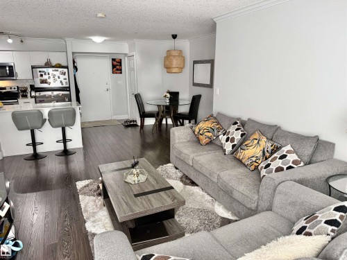 Living room featuring dark wood-style floors, ornamental molding, and a textured ceiling - 205 14604 125 Street, Edmonton, AB - Indoor Photo Showing Living Room