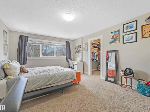 Spacious 5-bedroom layout with 3 bedrooms on the upper level—including a primary bedroom with luxurious ensuite—plus 2 additional bedrooms in the basement, perfect for guests, home office, or growing families. - 10941/10943 76 Avenue, Edmonton, AB - Indoor Photo Showing Bedroom