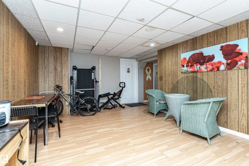 Workout room with wood walls, a drop ceiling, light wood-style flooring, and recessed lighting - 2349 Millbourne Road W, Edmonton, AB - Indoor