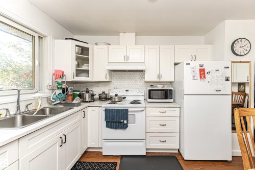 Kitchen with white appliances, white cabinetry, light countertops, and under cabinet range hood - 2349 Millbourne Road W, Edmonton, AB - Indoor Photo Showing Kitchen With Double Sink