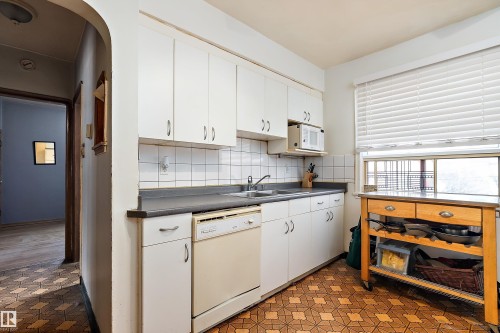 Kitchen featuring dark countertops, white cabinets, and white appliances - 10124 88 Avenue, Edmonton, AB - Indoor Photo Showing Kitchen With Double Sink