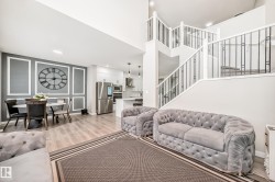 Living area featuring light wood finished floors, recessed lighting, a decorative wall, stairs, and a high ceiling - 
