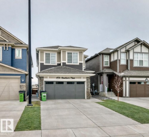 View of front of property with concrete driveway, a garage, and stone siding - 4930 Hawthorn Place, Edmonton, AB - Outdoor With Facade