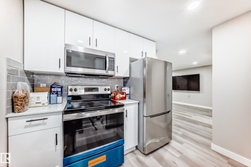Kitchen featuring stainless steel appliances, white cabinets, light wood finished floors, recessed lighting, and modern cabinets - 4930 Hawthorn Place, Edmonton, AB - Indoor Photo Showing Kitchen