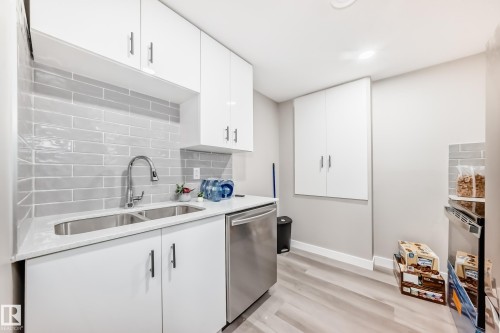 Kitchen with dishwasher, white cabinetry, light wood-style floors, tasteful backsplash, and recessed lighting - 4930 Hawthorn Place, Edmonton, AB - Indoor Photo Showing Kitchen With Double Sink