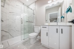 Bathroom featuring a marble finish shower, vanity, light marble finish floors, and recessed lighting - 