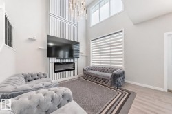 Living room with a glass covered fireplace, a high ceiling, wood finished floors, and a chandelier - 
