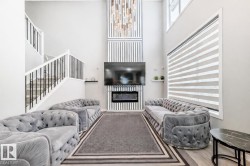 Living room featuring a glass covered fireplace, wood finished floors, a towering ceiling, and stairs - 