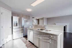 Kitchen with light stone countertops, appliances with stainless steel finishes, decorative backsplash, an island with sink, and light wood finished floors - 