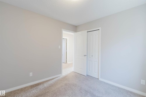 Unfurnished bedroom with light colored carpet, a closet, and a textured ceiling - 16627 18 Avenue, Edmonton, AB - Indoor Photo Showing Other Room