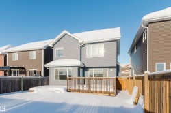 Snow covered rear of property with a fenced backyard and a deck - 