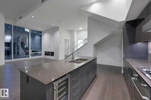 Kitchen with stainless steel appliances, wine cooler, dark wood-type flooring, a center island with sink, and open floor plan - 2303 10360 102 Street, Edmonton, AB - Indoor Photo Showing Kitchen With Double Sink With Upgraded Kitchen