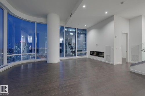 Unfurnished living room featuring expansive windows, dark wood-type flooring, and recessed lighting - 2303 10360 102 Street, Edmonton, AB - Indoor