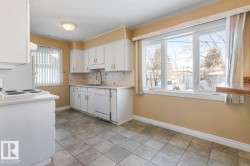 Kitchen with backsplash, light countertops, white cabinets, white appliances, and light tile patterned floors - 