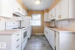 Kitchen featuring white appliances, tasteful backsplash, light countertops, under cabinet range hood, and white cabinets - 