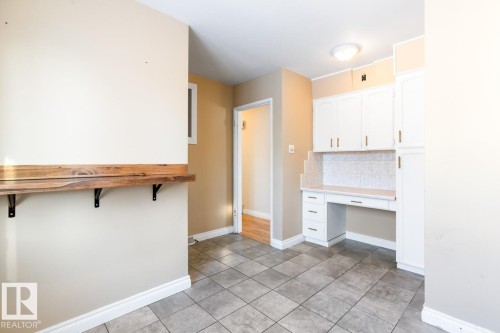 Kitchen with built in desk, white cabinets, backsplash, and light countertops - 7324 77 Street, Edmonton, AB - Indoor Photo Showing Other Room