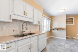 Kitchen featuring light countertops, white cabinets, and dishwasher - 