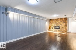 Unfurnished living room with dark wood finished floors, wood walls, and a fireplace - 