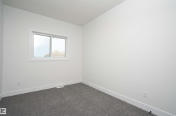 Spare room featuring baseboards and dark colored carpet - 