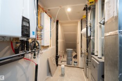 Utilities featuring heating unit, tankless water heater, and electric panel - 