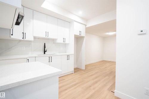 Kitchen with white cabinetry, light wood finished floors, light stone counters, exhaust hood, and recessed lighting - 430 Crystal Creek Link, Leduc, AB - Indoor Photo Showing Kitchen
