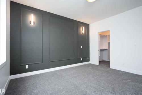 Unfurnished bedroom with a walk in closet, carpet flooring, and a decorative wall - 430 Crystal Creek Link, Leduc, AB - Indoor Photo Showing Other Room