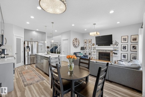 Dining area featuring a stone fireplace, light wood-type flooring, recessed lighting, stairway, and a textured ceiling - 17727 13 Avenue, Edmonton, AB - Indoor With Fireplace