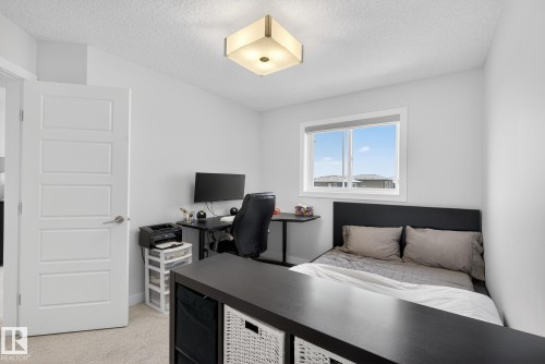 Bedroom featuring a textured ceiling, light carpet, and a desk - 17727 13 Avenue, Edmonton, AB - Indoor